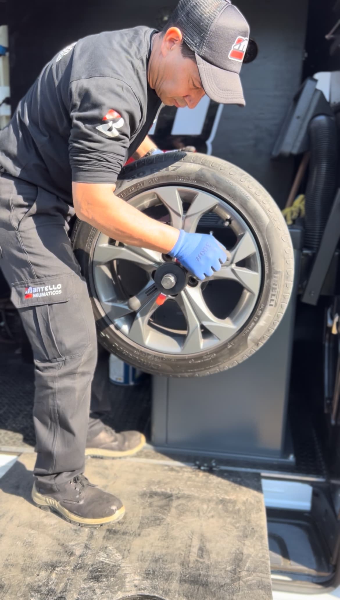 Técnico Mantello operando balanceadora profesional con neumático - Equipamiento móvil de precisión
